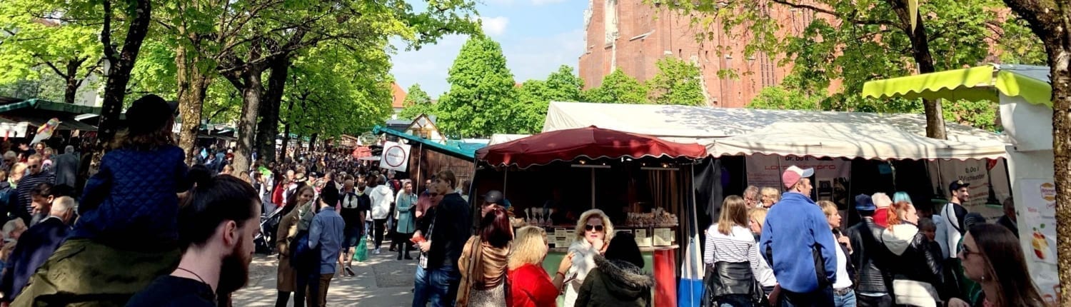 Ein Straßenmarkt mit vielen Menschen und der Mariahilfkirche im Hintergrund